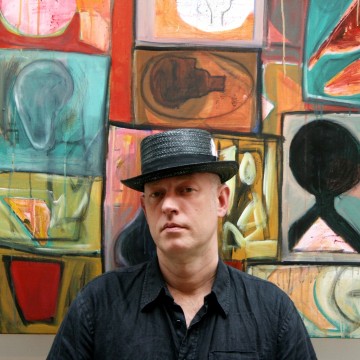 Man in black hat and black shirt against multicolour painting tile wall background