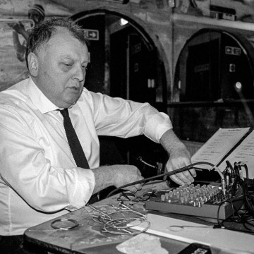 Black and white image of man in white shirt using audio equipment
