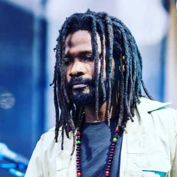 Man with dreadlocks wearing beads and white shirt