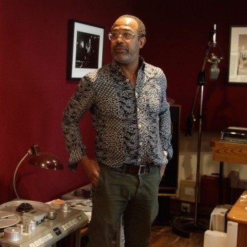 Black man with glasses in patterned shirt in recording studio background