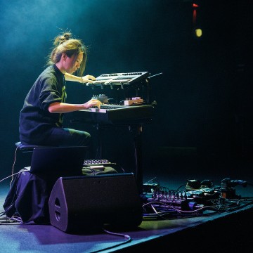 Woman on dark stage playing keyboards