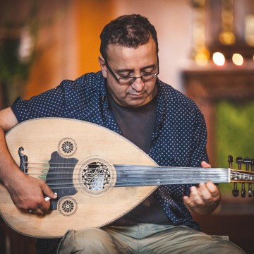 Man with glasses playing Oud instrument