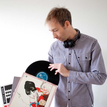 Man in chequered shirt and headphones with vinyl records