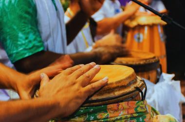 Close-up Photograph of hands hitting Brazilian drum with other drummers in background