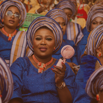 Crowd of Black women in African dress, centre woman with mini electric fan